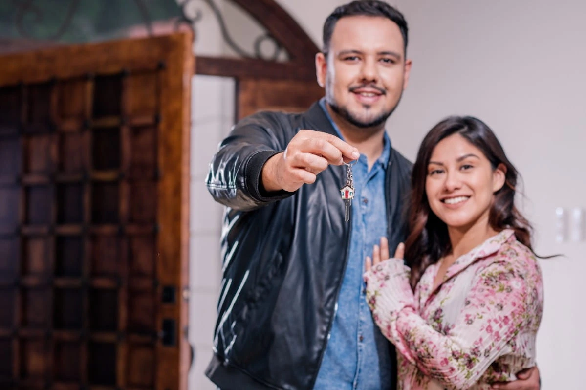 Pareja sonriente mostrando las llaves de su nueva propiedad