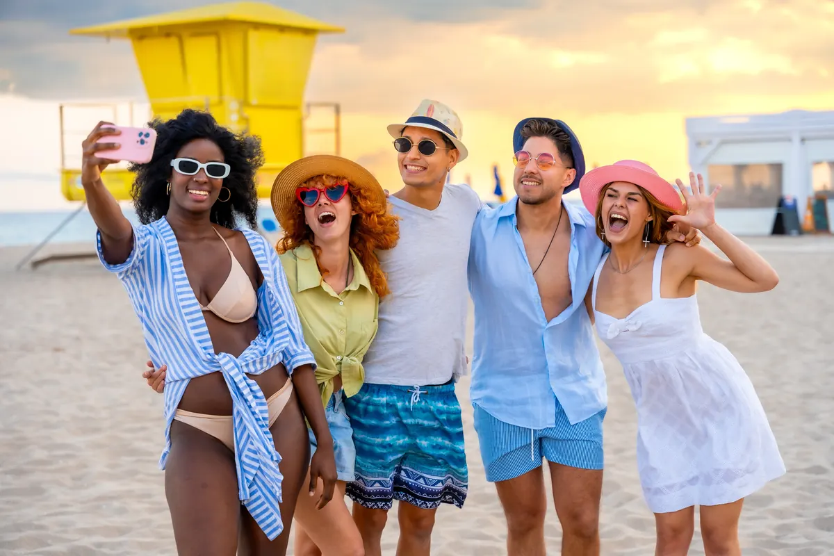 Grupo de amigos tomándose una selfie en una playa de Miami al atardecer