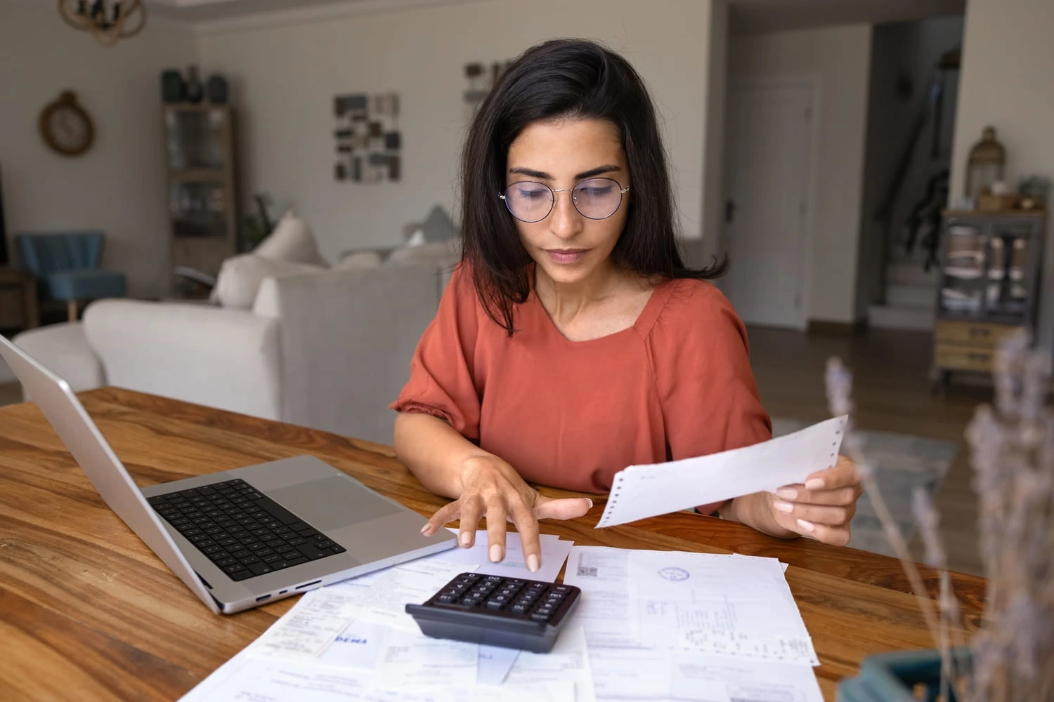 Mulher revisando contas e documentos financeiros com uma calculadora, ao avaliar os custos de comprar um imóvel em Miami em comparação com o México