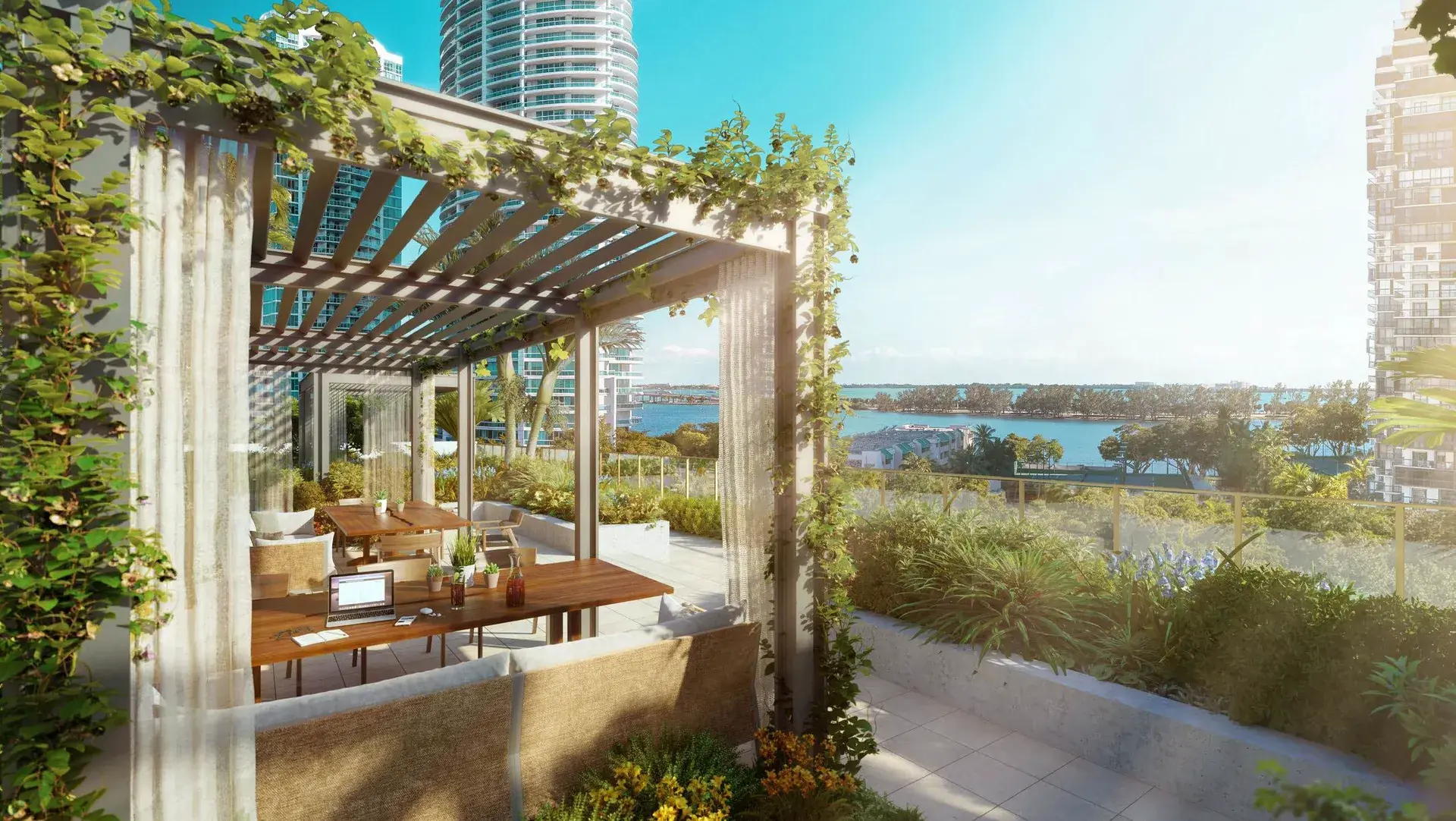 2200 Brickell — comedor exterior bajo una pérgola cubierta de enredaderas, con la bahía y la vegetación al fondo