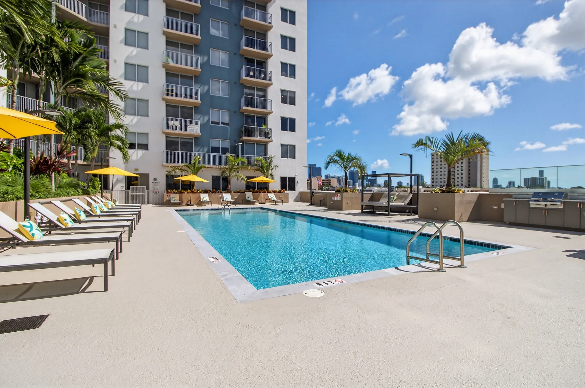 Centralis Residences — terraza de piscina con camastros, sombrillas amarillas y la fachada del edificio al fondo
