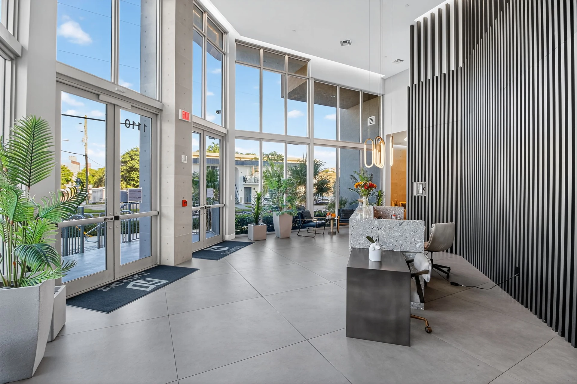 Centralis Residences — lobby de doble altura con fachada acristalada y celosía vertical de metal