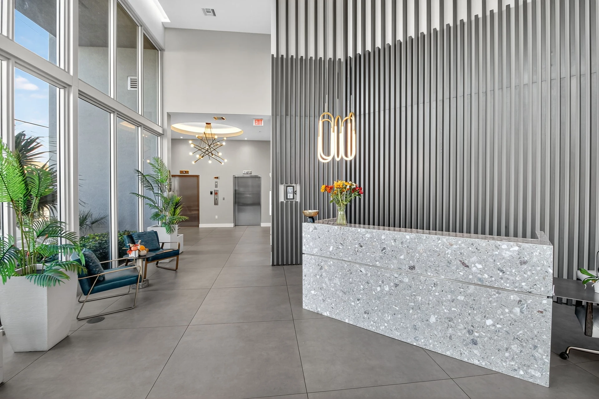 Centralis Residences — lobby de acceso con mostrador de recepción y celosía vertical de doble altura