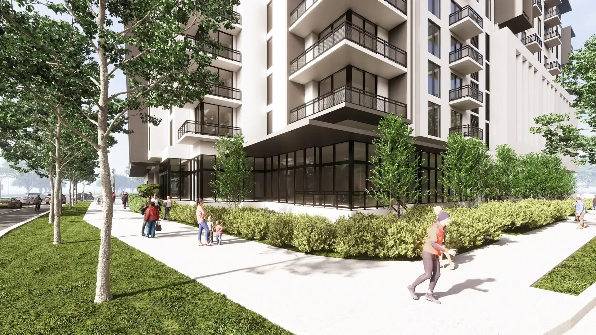 River District 14 — el acceso peatonal del edificio, con la carpintería oscura de la planta baja, el césped, los árboles jóvenes y residentes caminando por la acera