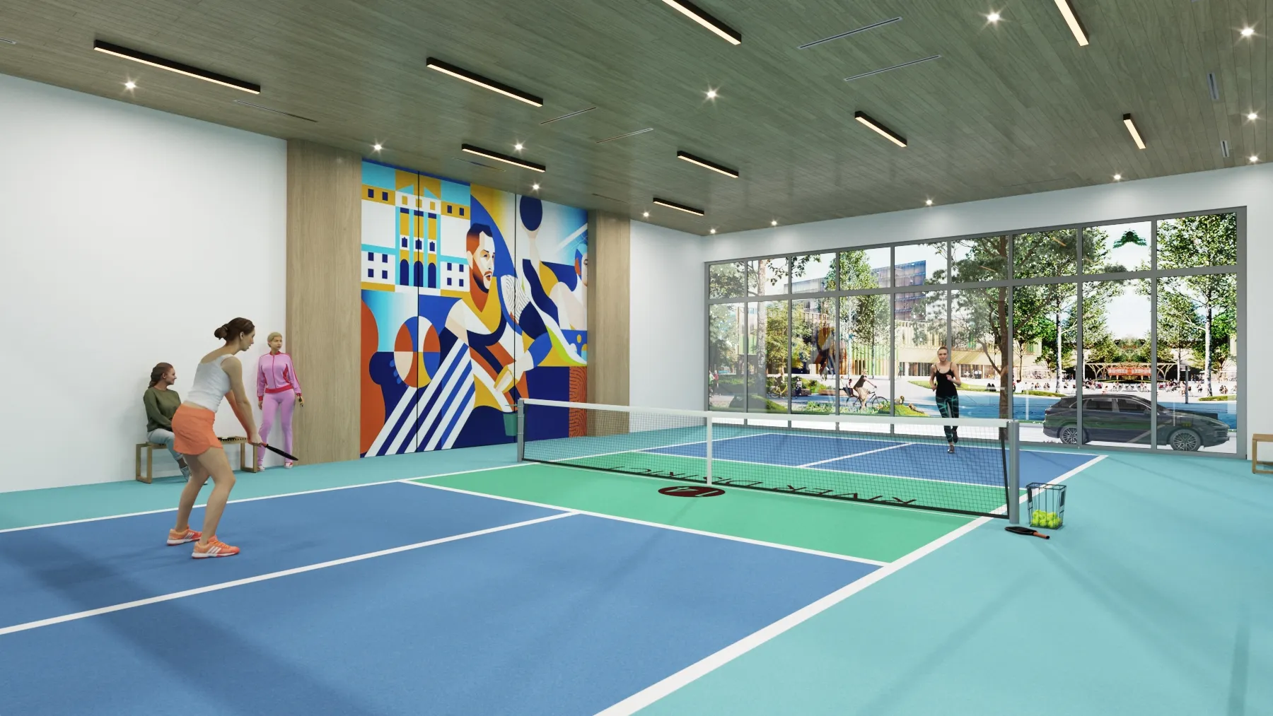 River District 14 — cancha de pickleball bajo techo con piso azul y verde, red montada, mural de color en el muro del fondo y ventanales hacia la calle