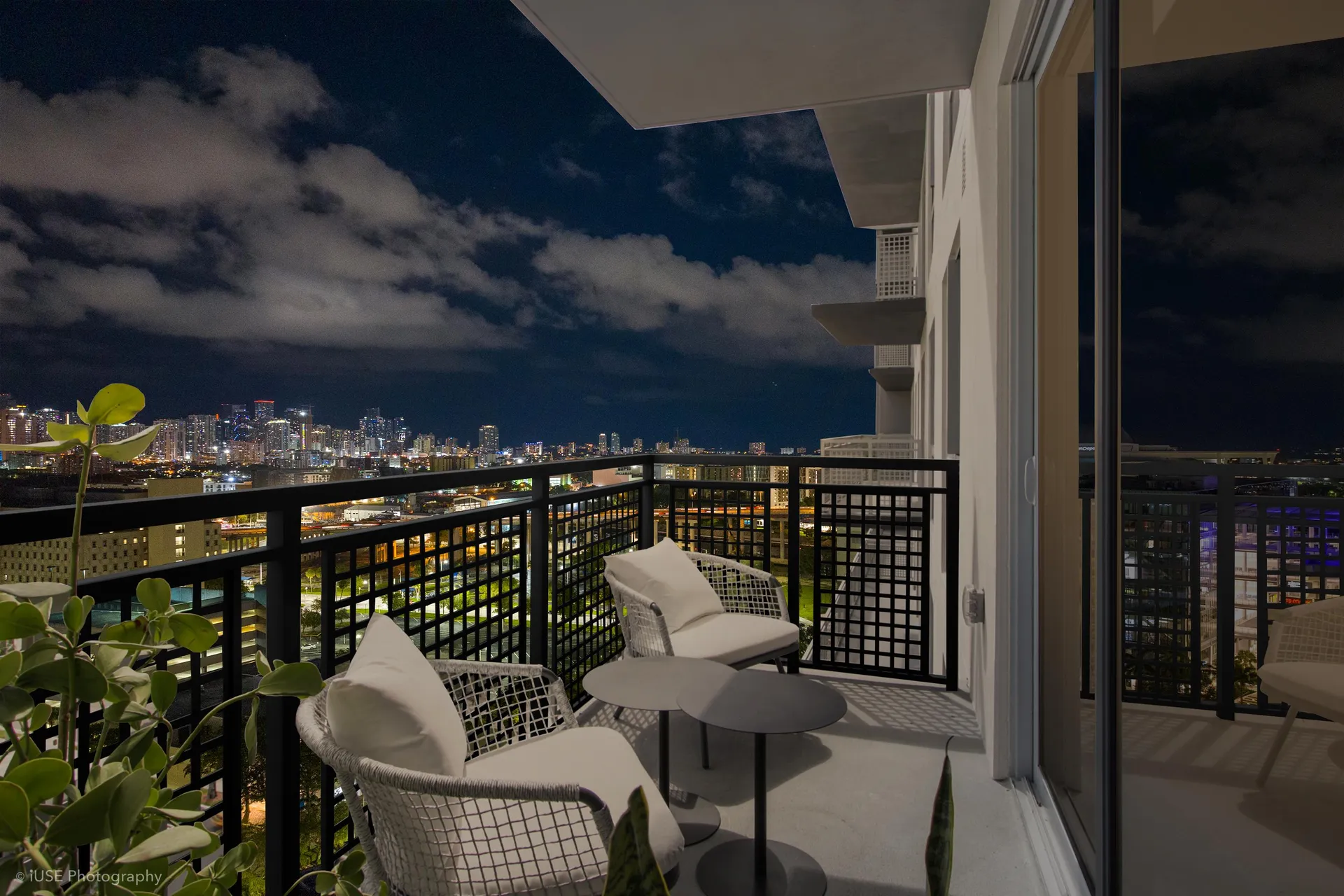 River District 14 — balcón privado de noche, con dos sillones tejidos, mesa auxiliar y el skyline de Miami iluminado al fondo