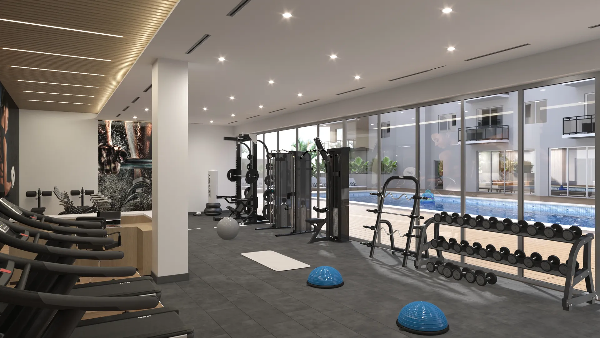River District 14 — gimnasio interior con hilera de caminadoras, torres de fuerza, rack de mancuernas y ventanales corridos que dan al patio de la piscina