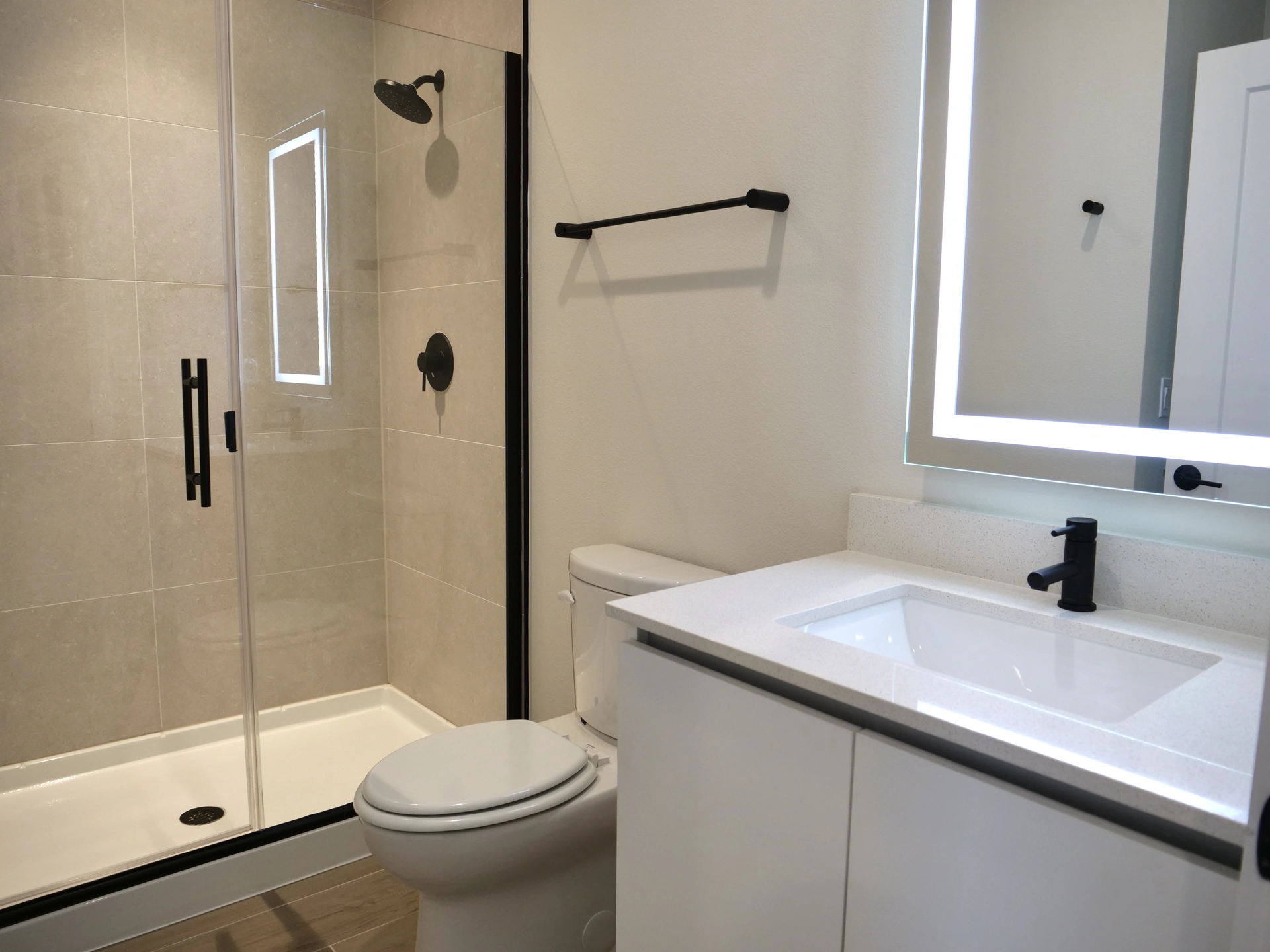 Tranquility Townhomes — baño con ducha de vidrio y tocador con espejo iluminado