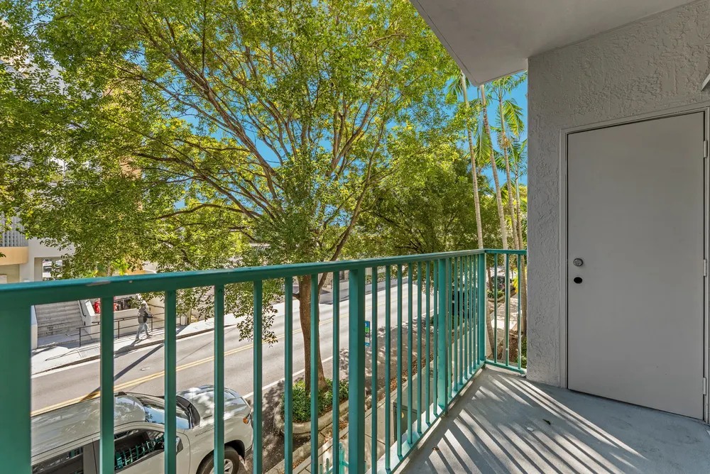 Valencia South Miami — balcón privado con vista a la calle arbolada frente al edificio