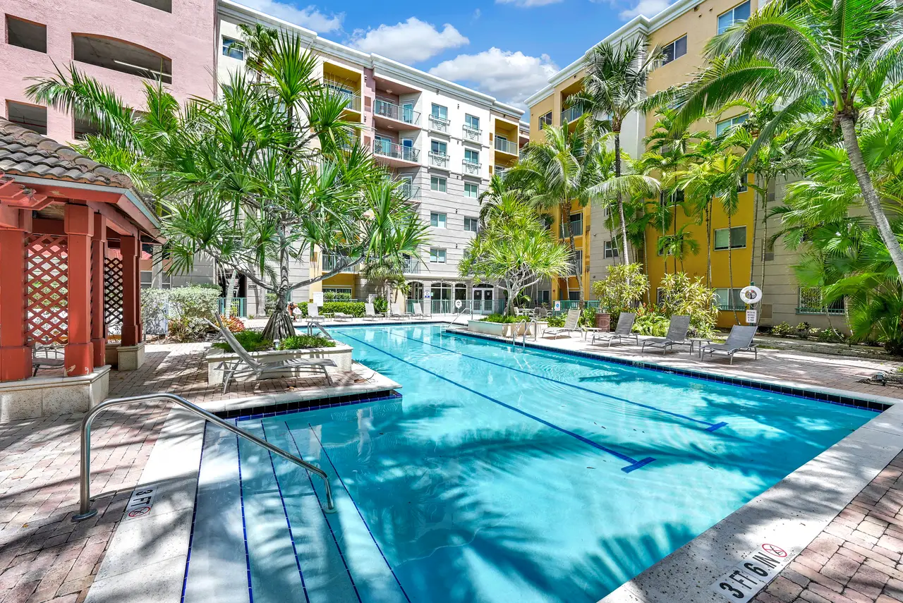 Valencia South Miami — piscina con cabaña de palapa, camastros y la fachada del edificio al fondo