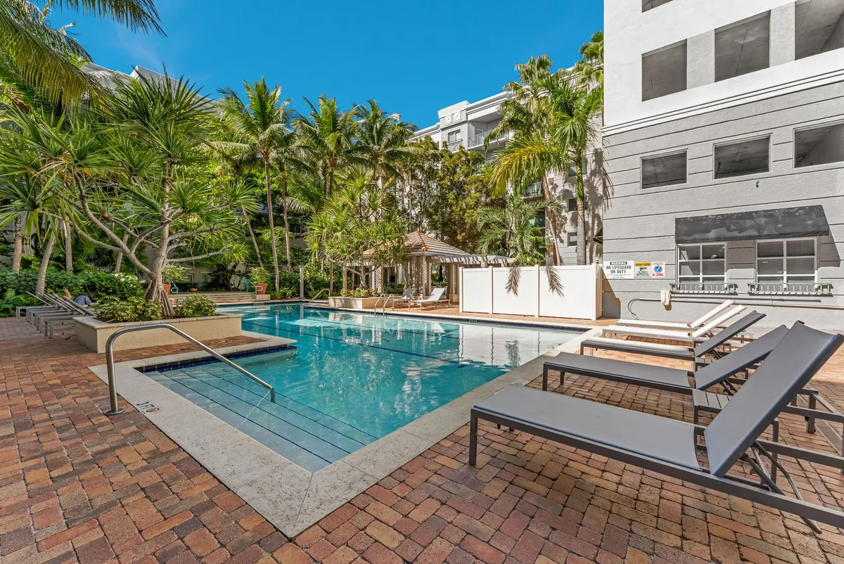 Valencia South Miami — piscina de la comunidad con reposeras, sombrillas y el pérgola de la terraza